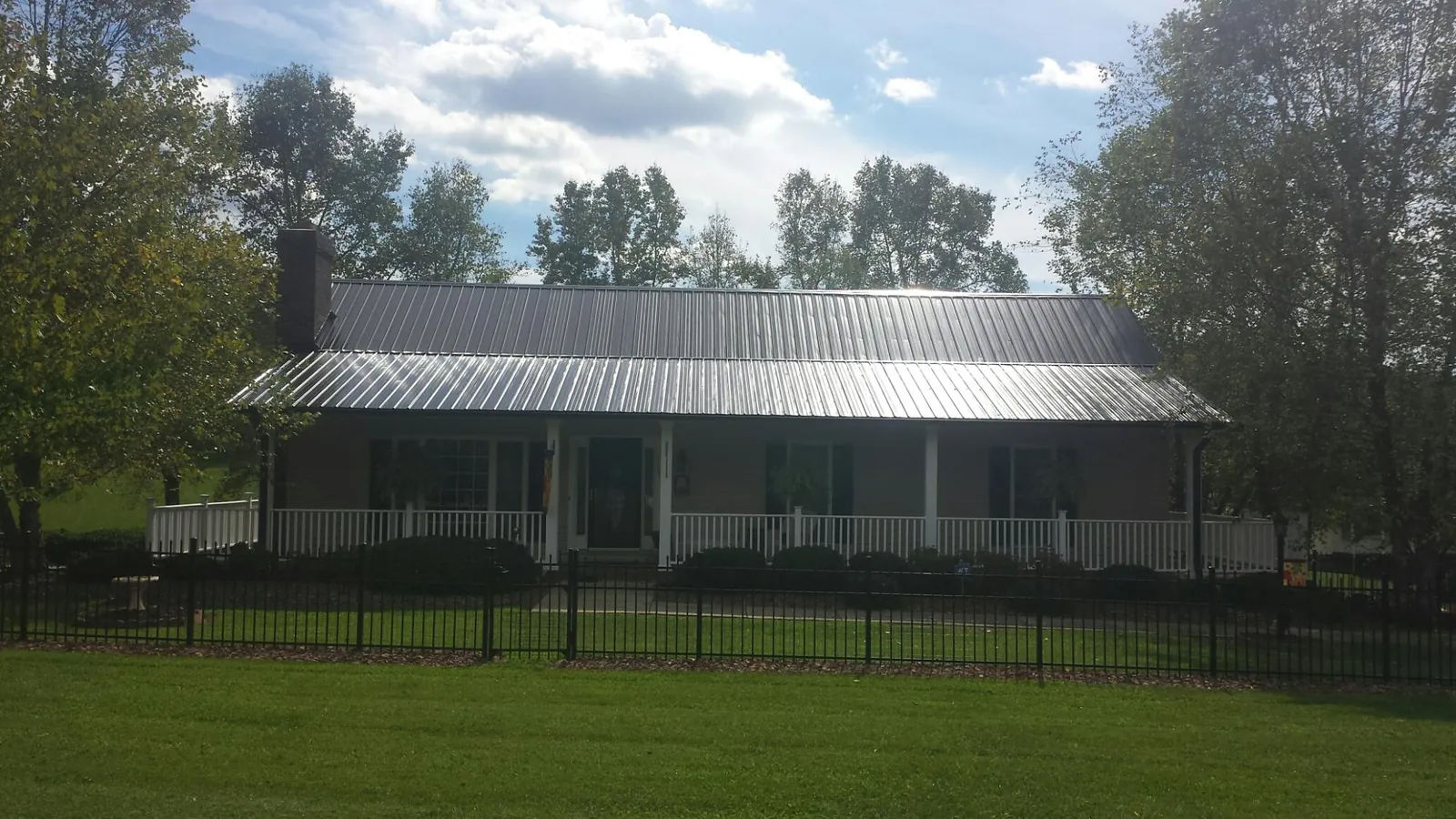 Gray metal roof on a brick ranch with a full width front porch — Gutter Guard Installation work by our crew in Brooklyn
