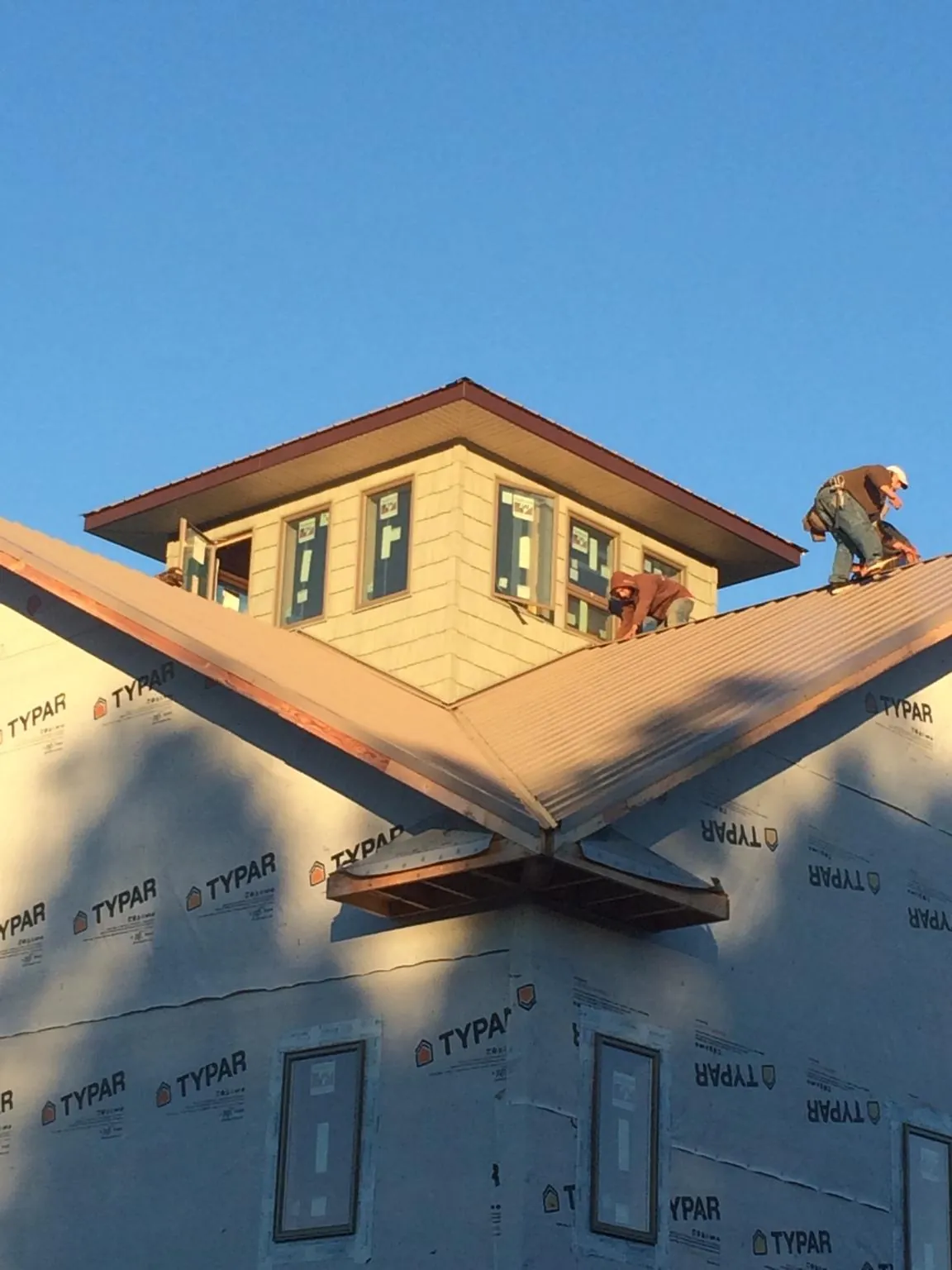 Roofers working around a rooftop cupola on a new metal roof at sunset — Roof Waterproofing in Brooklyn by Roofing Brothers